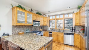 A kitchen with granite countertops, wooden cabinets, stainless steel appliances, and a window providing natural light.
