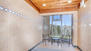 A bathroom with a bathtub, two chairs, and a table.