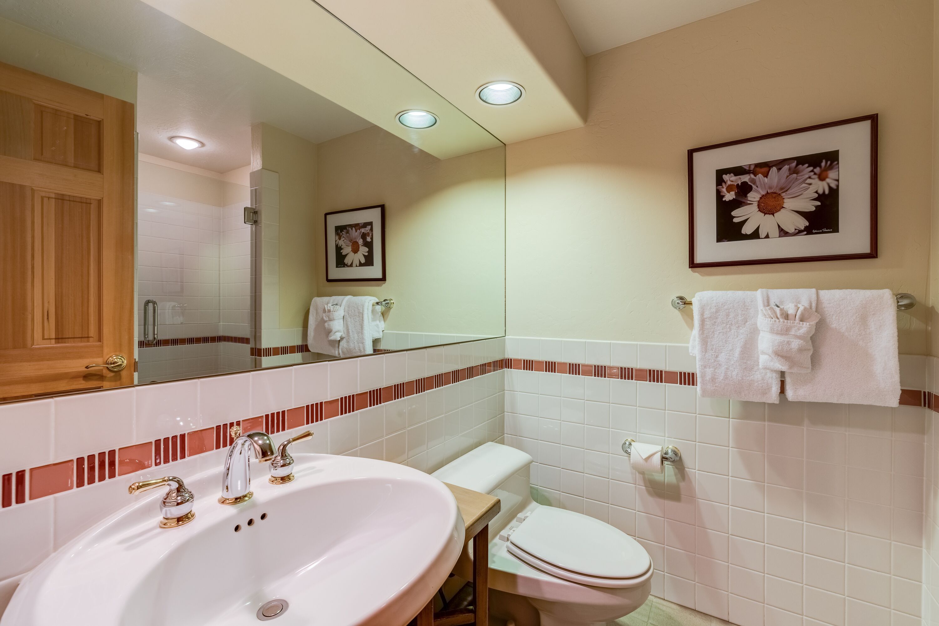 Een badkamer met een wit wastafel, toilet en spiegel.