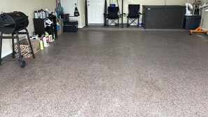 Uma garagem com churrasqueira, materiais de limpeza e cadeiras dobráveis.