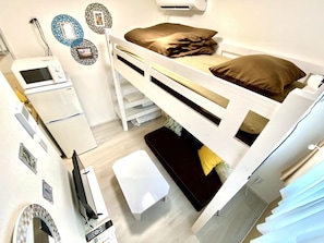 A bunk bed room with a desk, a mirror, and a TV.