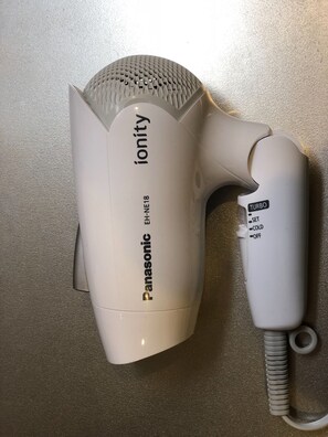 Un sèche-cheveux Panasonic doté d’un embout concentrateur, posé sur une surface texturée.