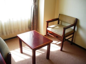 Una habitación con una mesa de madera, una silla, suelo alfombrado y un radiador.