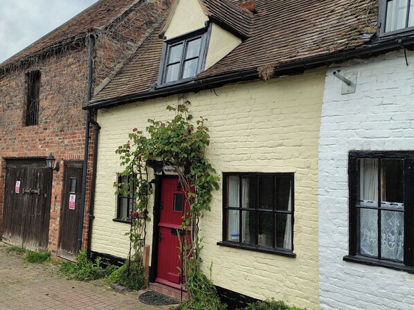 A traditional building with a red door, white walls, and a brick section. - Runnymede (Tewkesbury)