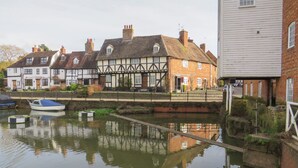 A canal with traditional half-timbered houses on one side and a white building on the other. - Runnymede (Tewkesbury)