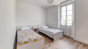 Ein Schlafzimmer mit zwei Betten, einem Fenster und einer Heizung.