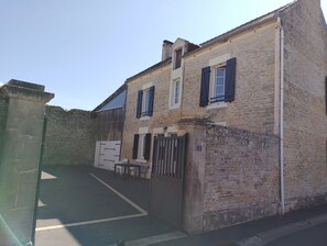 Un edificio de piedra con una entrada porticada, un letrero con el número 3 y un pequeño espacio al aire libre para sentarse.