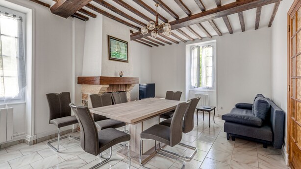 Ein geräumiger Essbereich mit Holztisch und modernen Stühlen, eine Küchenzeile mit eingebautem Ofen und eine gemütliche Sitzecke mit einer Couch.