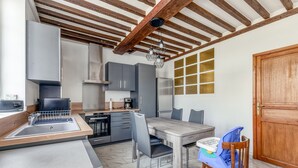 Eine moderne Küche mit grauen Schränken, einem Holzessttisch und einem Hochstuhl für Babys.
