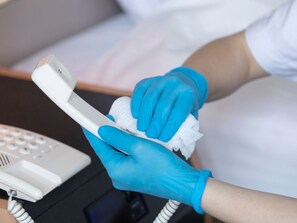 Una persona con guantes azules sostiene un teléfono blanco.