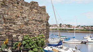 A stone wall with a view of boats and houses in the background. - Y Bwthyn (Conwy)