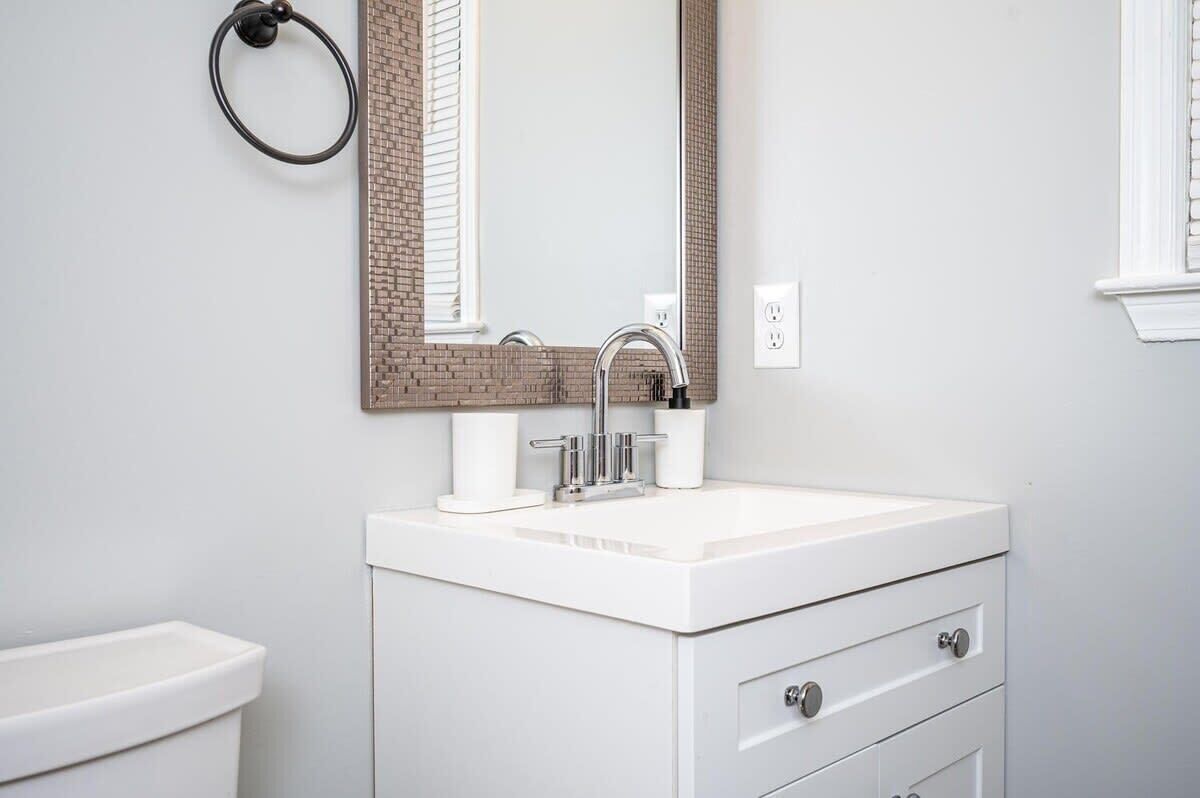 A bathroom with a white sink, a mirror, and a toilet.