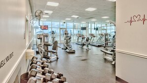 Et fitnessrum med forskellig træningsudstyr, et fjernsyn og en motiverende besked på væggen.