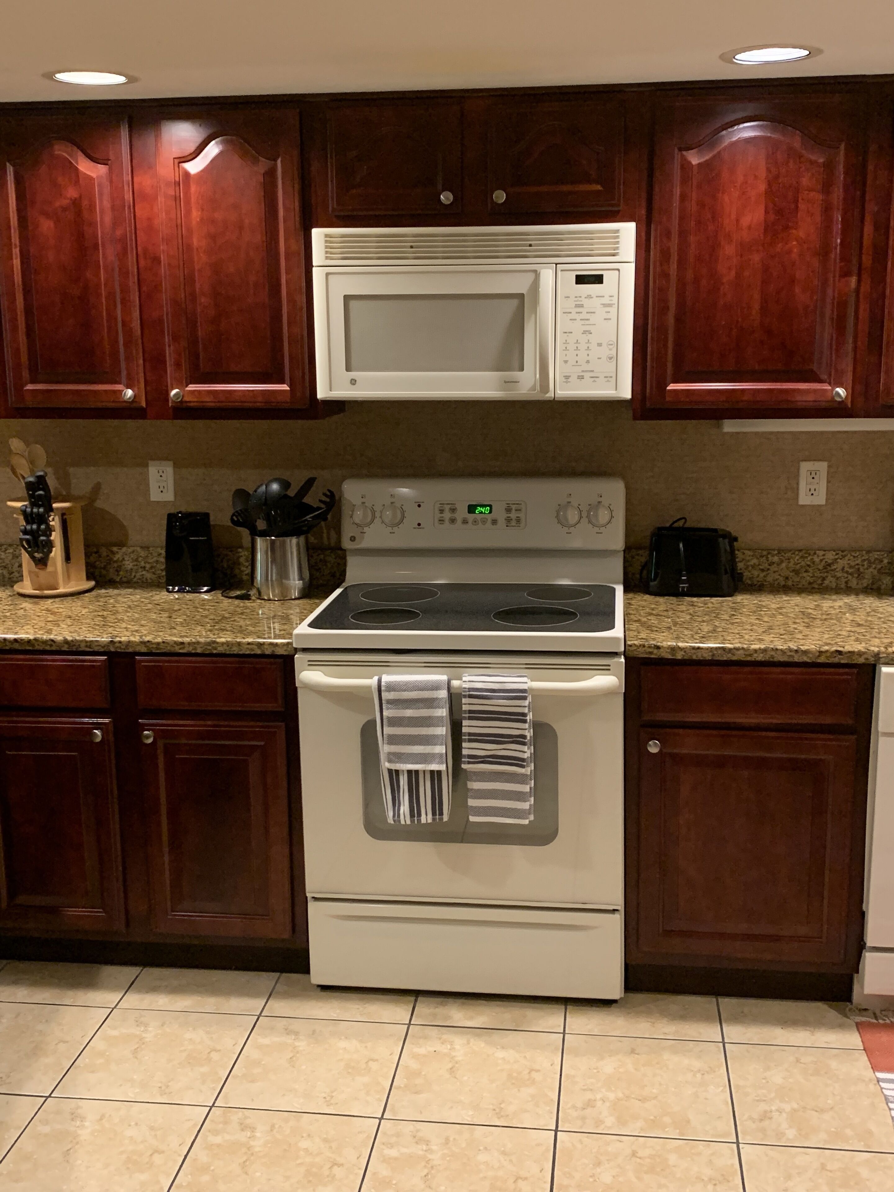 A kitchen with wooden cabinets, a microwave, a stove, and a coffee maker.
