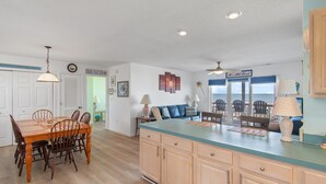 A spacious kitchen with a large island, wooden cabinets, and a dining area with chairs. - "All Good" Oceanfront 2 bedrooms, 2 bathrooms. (Holden Beach)