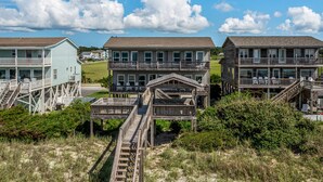 A beachfront property with multiple buildings, including a two-story house with a balcony and a wooden deck.