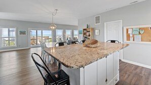 A spacious kitchen with a large island, white cabinetry, and a view of the outdoors.