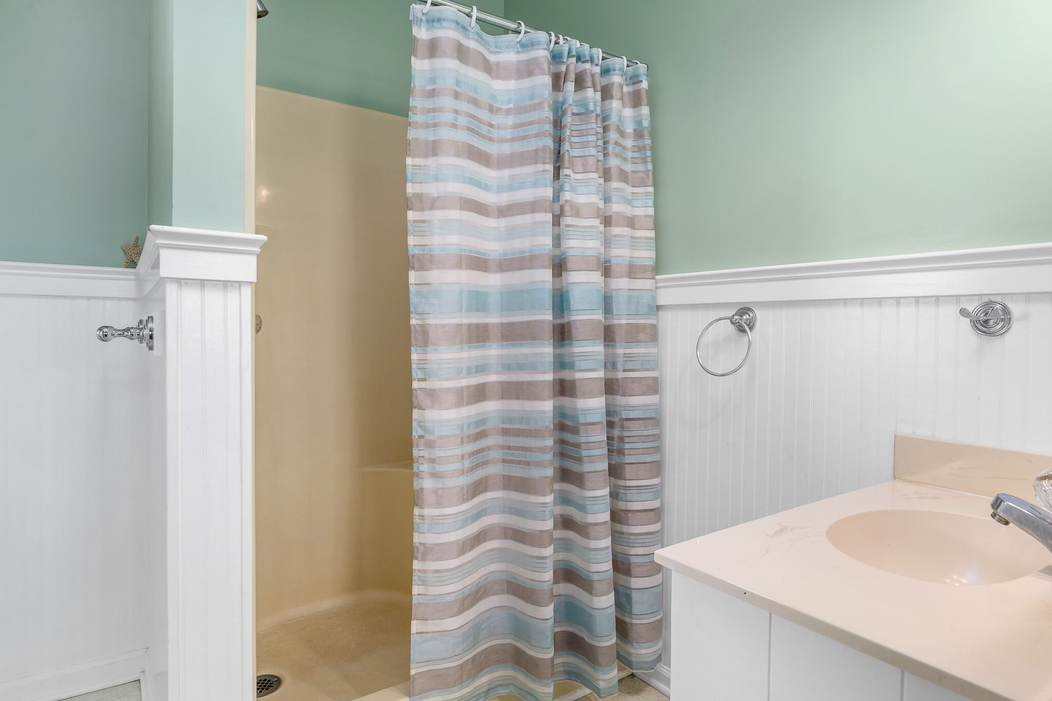 A bathroom with a shower curtain, a sink, and a mirror.