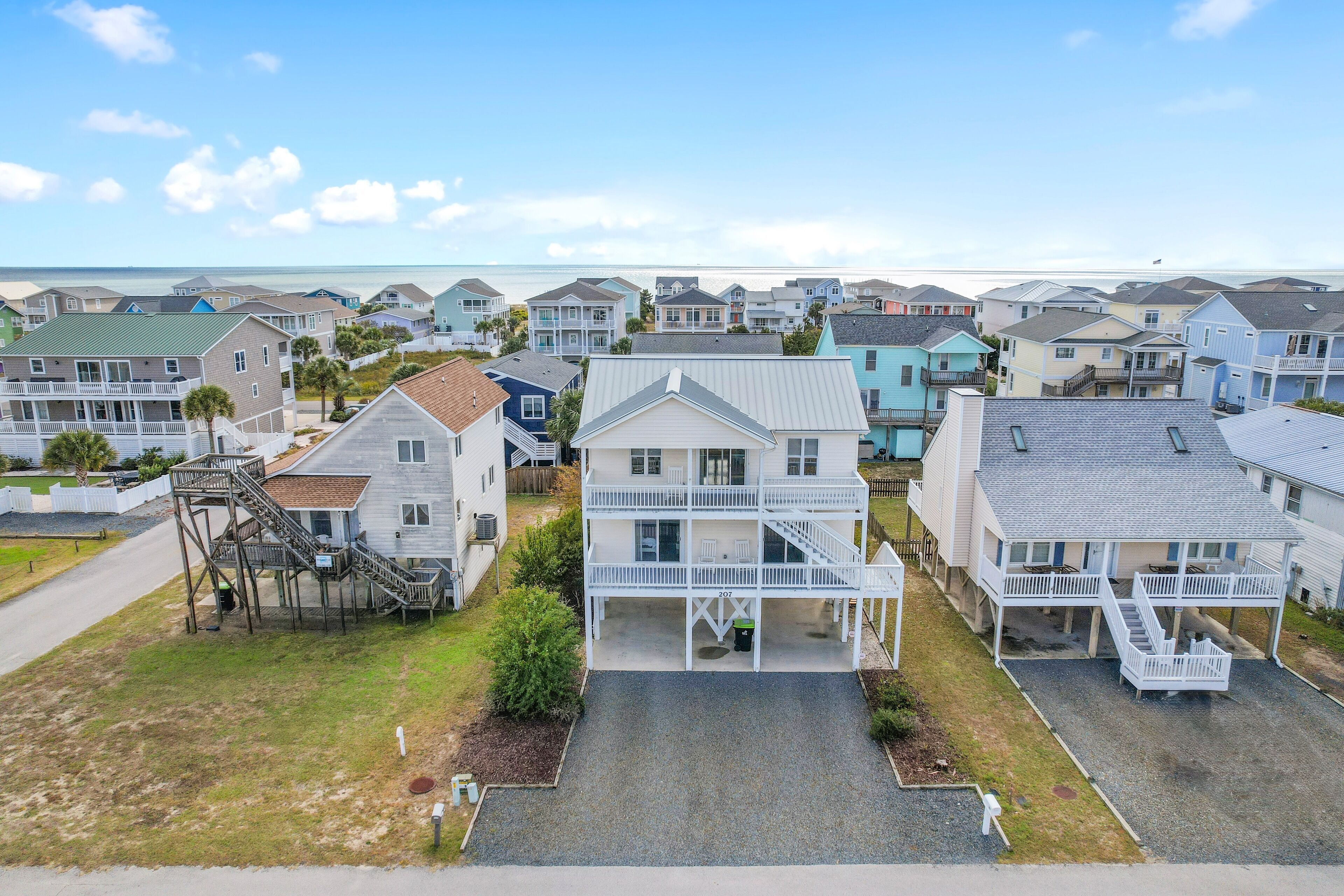A coastal residential area with multiple two-story houses featuring front porches and a prominent staircase leading to the upper floor.