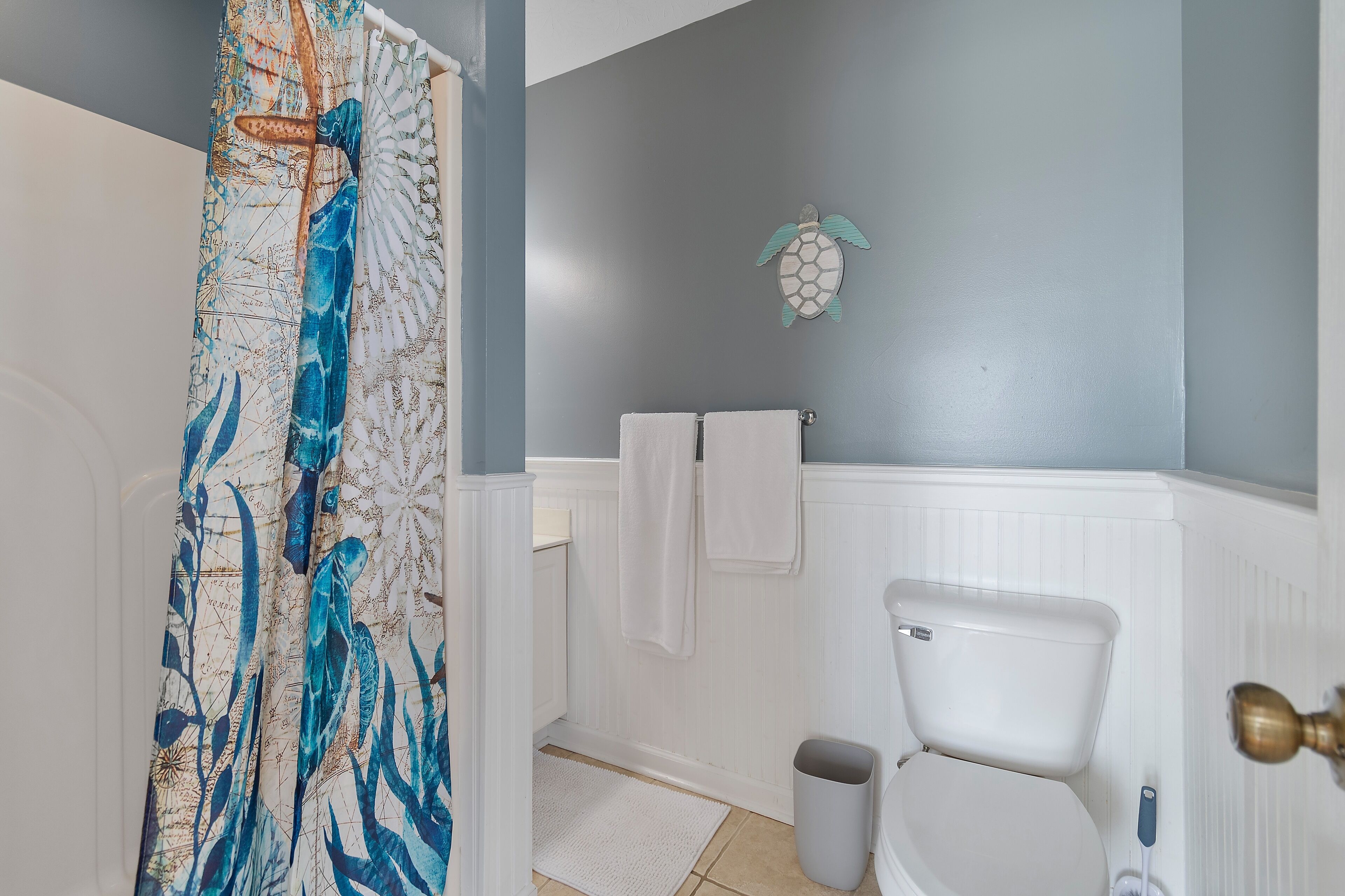 A bathroom with a toilet, a shower curtain, and a towel rack.