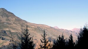 Eine Berglandschaft mit vereinzelten Bäumen und blauem Himmel.