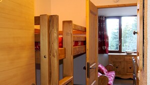 Ein Zimmer mit einem Holzbett mit zwei Etagen, einem Fenster und einem Schreibtisch.