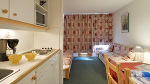 A compact room with a kitchenette, a sofa bed, and a dining table.