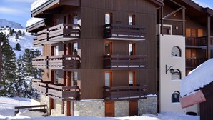 A multi-story wooden building with balconies, stone foundation, and snow-covered surroundings.