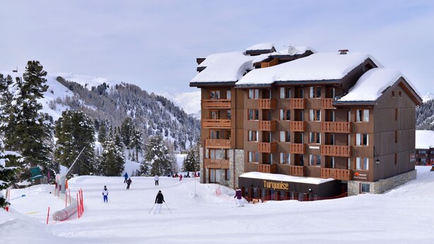 Un hotel de varios pisos con balcones y un letrero que dice "Turquoise".