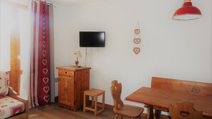 Una habitación acogedora con un escritorio de madera, una silla y un televisor instalado en la pared.