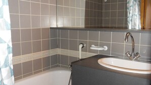 Un baño con bañera, lavamanos y espejo.