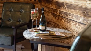 A round wooden table with a bottle of wine, two glasses, and a magazine.