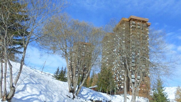 Een meerlaags gebouw met een modern architectonisch ontwerp, omringd door bomen en bedekt met sneeuw.