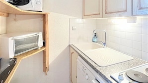 Eine kleine Küche mit Mikrowelle, Toaster, Wasserkocher und Geschirrspüler.
