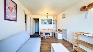 Ein kompakter Wohnbereich mit Sofa, Esstisch mit Stühlen, einer Bank und einer Heizung.