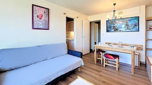Ein gemütliches Wohnzimmer mit einer Couch, einem Esstisch mit Stühlen und einer Küche im Hintergrund.