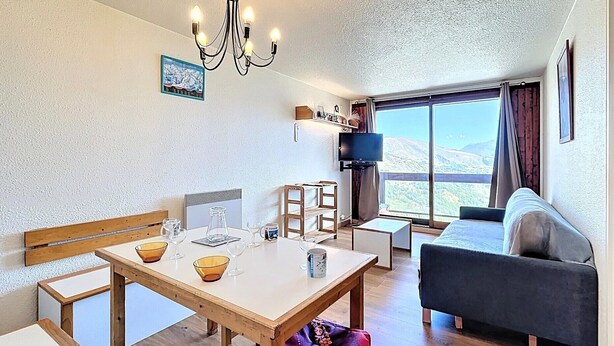 Ein modernes Wohnzimmer mit einem Holzesstisch, einer Couch und einem an der Wand befestigten Fernseher.