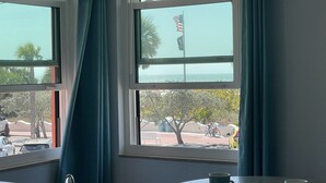 Ein Zimmer mit Blick auf das Meer und eine Flagge vor der Fassade. Ein Tisch mit einer Tasse darauf.