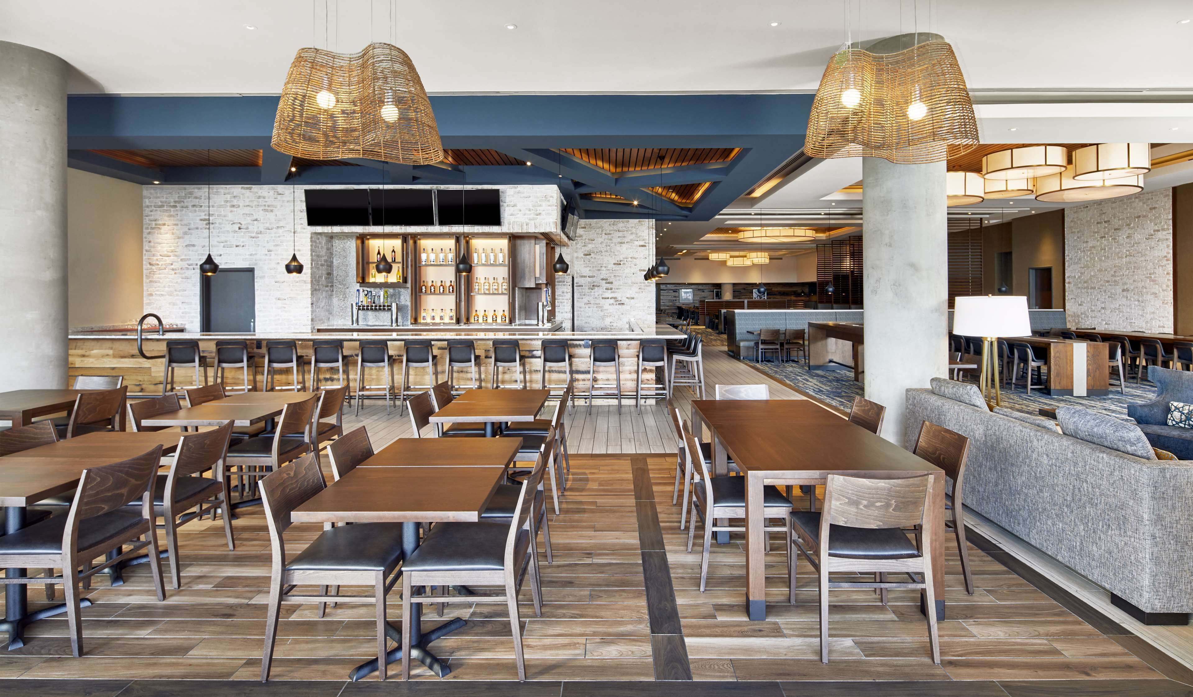 Un restaurant spacieux avec des tables et des chaises hautes, un bar et un coin salon avec des canapés et une table basse.