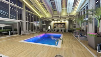 Une piscine intérieure avec des chaises longues et un espace bar.