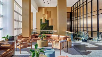 Un lobby moderno con sofás de cuero, detalles de madera y una pared decorativa verde.