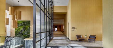 A modern interior with a glass wall, escalator, and seating area.