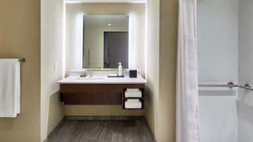 A modern bathroom with a large mirror, a sink, and a shower.