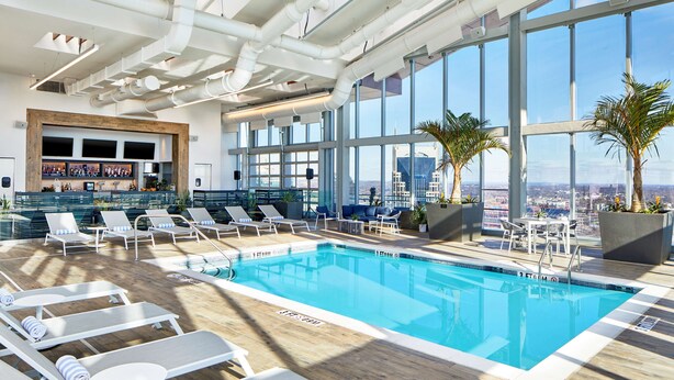 A modern indoor pool with clear blue water, surrounded by sun loungers and potted plants. - Embassy Suites by Hilton Nashville Downtown (Nashville)