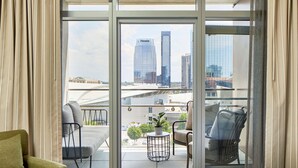 A hotel room with a balcony, a bed, a sofa, and two chairs. - Embassy Suites by Hilton Nashville Downtown (Nashville)