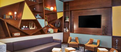 A modern living room with a sectional sofa, two armchairs, and a TV wall unit.