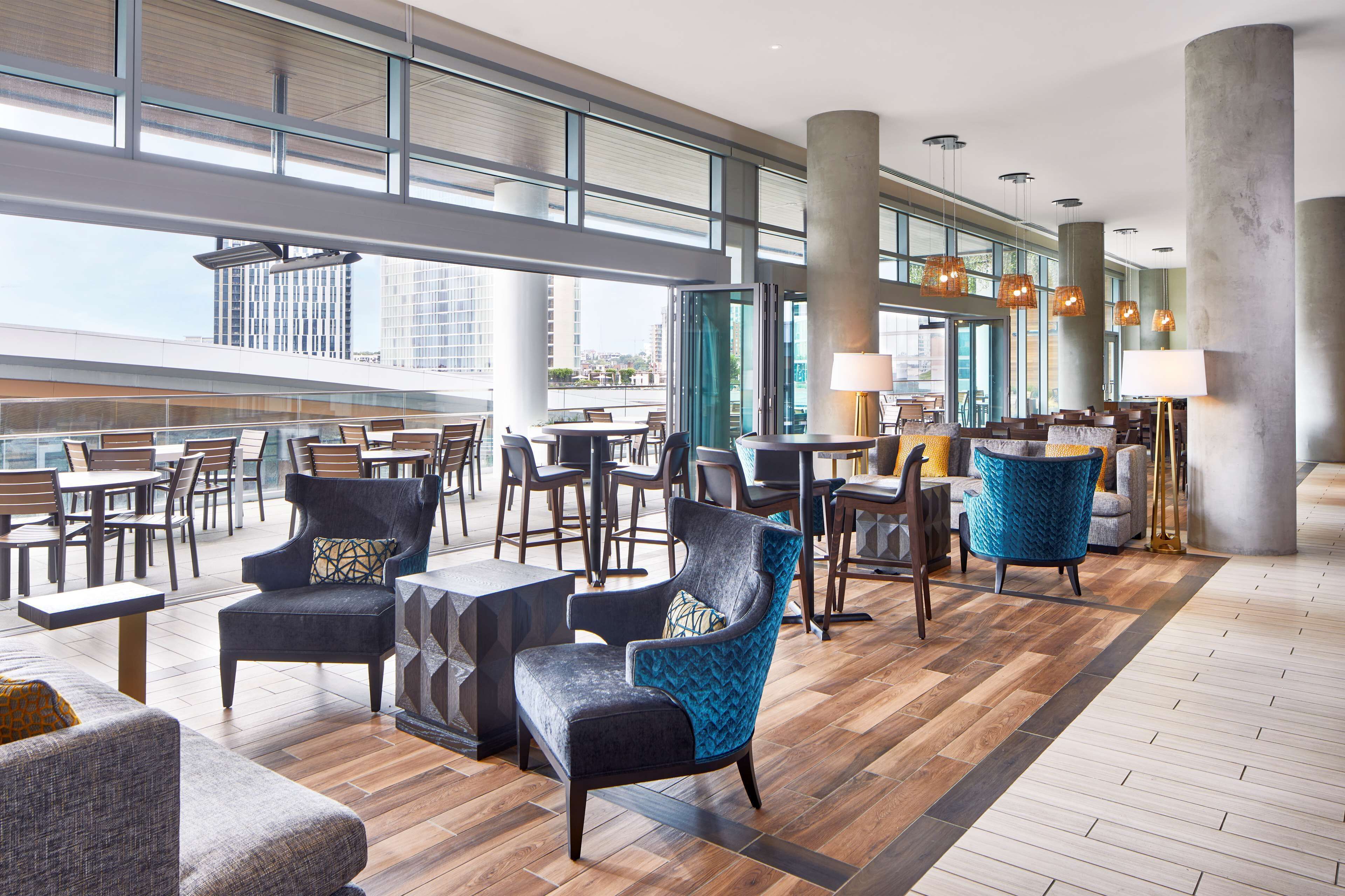 A spacious lobby with high ceilings, large windows, and a variety of seating arrangements including sofas, chairs, and tables.