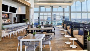 A modern bar area with high ceilings, large windows, and a city view. - Embassy Suites by Hilton Nashville Downtown (Nashville)