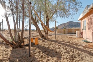 Relax in a serene desert oasis with a hammock and bench amidst a tranquil landscape.