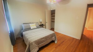 A bedroom with a bed, a nightstand, a lamp, and a closet.